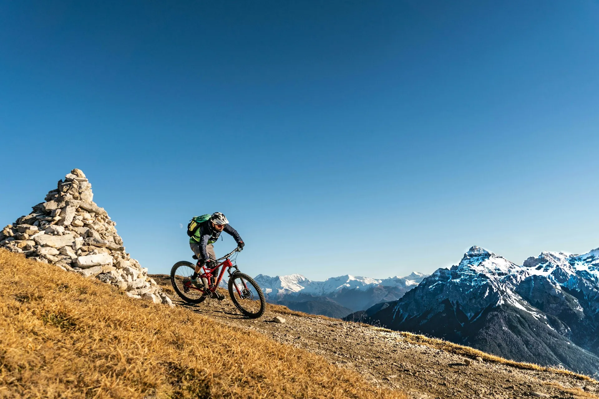Biker su e-MTB in cima con le Dolomiti innevate sullo sfondo